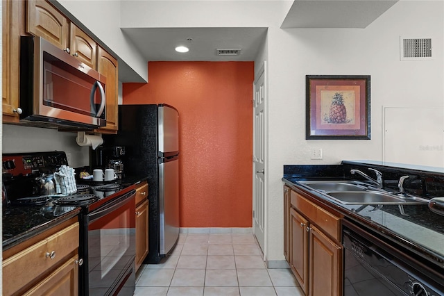 kitchen featuring dark stone countertops, light tile patterned floors, sink, and black appliances