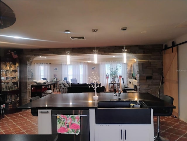 kitchen featuring white cabinetry, sink, decorative light fixtures, and a barn door