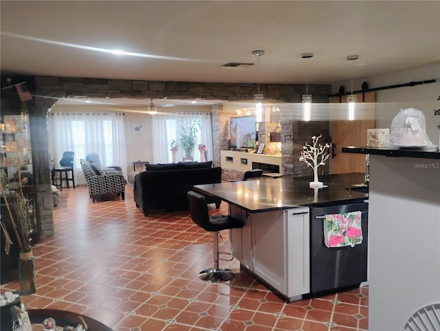 kitchen featuring white cabinets, stainless steel refrigerator, hanging light fixtures, and a kitchen bar