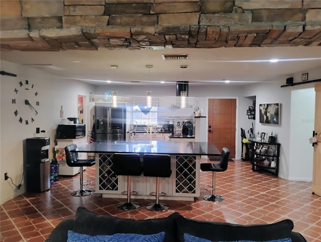 bar featuring dark tile patterned floors, stainless steel appliances, hanging light fixtures, and sink