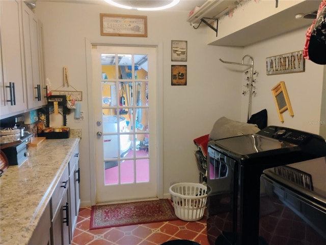 clothes washing area with tile patterned flooring, washing machine and clothes dryer, and cabinets