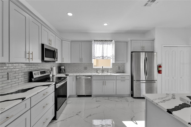 kitchen featuring tasteful backsplash, stainless steel appliances, sink, and light stone counters