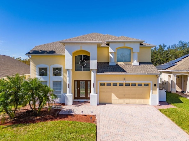 mediterranean / spanish-style house featuring a garage, a front lawn, and central AC unit