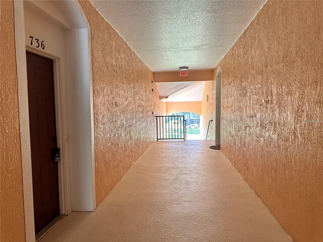 corridor with a textured ceiling and carpet floors