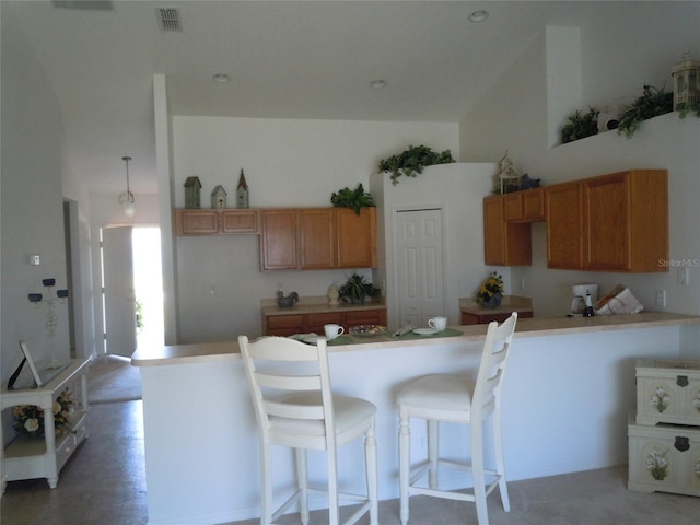 kitchen with kitchen peninsula, a kitchen bar, and high vaulted ceiling