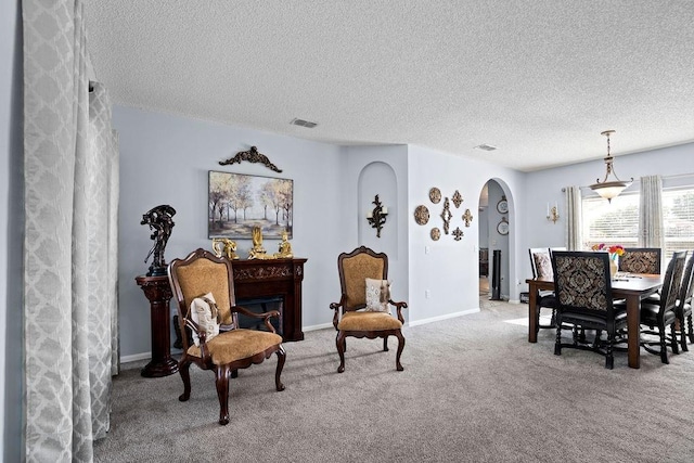 living area featuring visible vents, arched walkways, baseboards, and carpet flooring