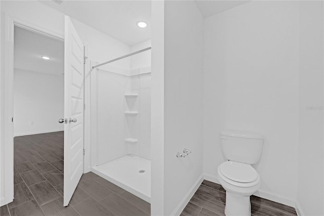 bathroom featuring walk in shower, hardwood / wood-style floors, and toilet