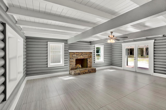 unfurnished living room featuring wood ceiling, ceiling fan, beamed ceiling, and a stone fireplace