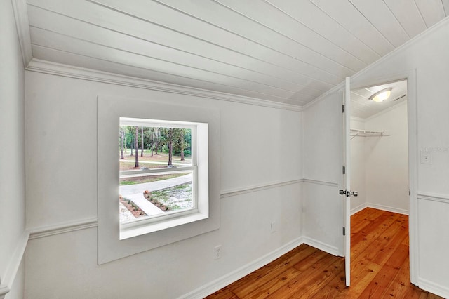 empty room featuring light hardwood / wood-style flooring, lofted ceiling, and crown molding