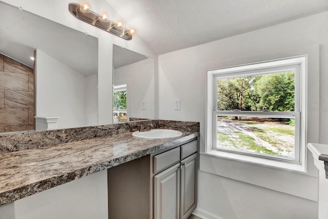 bathroom with a textured ceiling, vanity, and vaulted ceiling