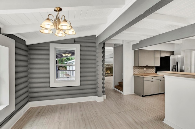 interior space featuring stainless steel fridge, gray cabinetry, log walls, backsplash, and decorative light fixtures