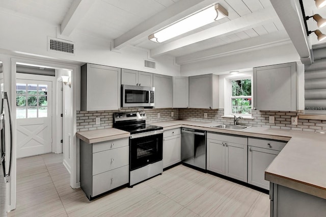 kitchen with appliances with stainless steel finishes, plenty of natural light, sink, and gray cabinetry