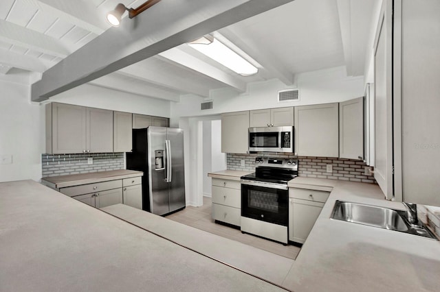 kitchen featuring sink, beam ceiling, tasteful backsplash, appliances with stainless steel finishes, and light hardwood / wood-style floors