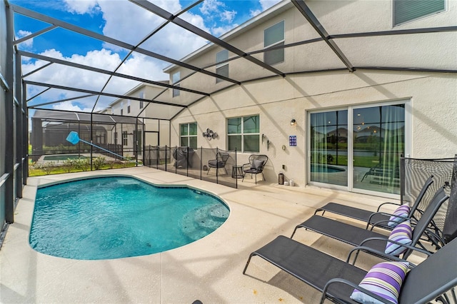 view of pool with glass enclosure and a patio area