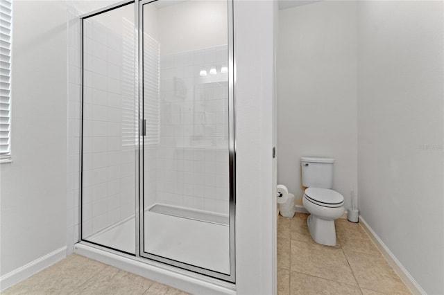 bathroom featuring toilet, a shower with door, and tile patterned flooring