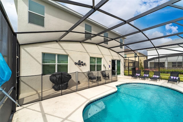 view of pool with glass enclosure and a patio area