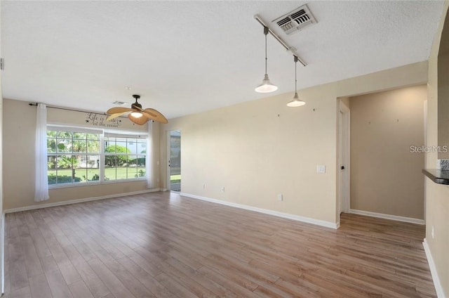 unfurnished room with ceiling fan, hardwood / wood-style flooring, track lighting, and a textured ceiling