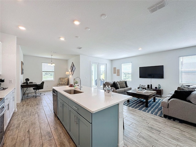 kitchen with sink, stove, dishwasher, an island with sink, and french doors