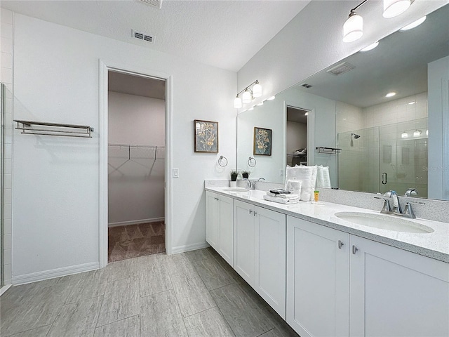 bathroom featuring a textured ceiling, a shower with shower door, and vanity