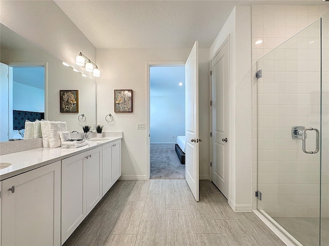 bathroom with a textured ceiling, vanity, and an enclosed shower