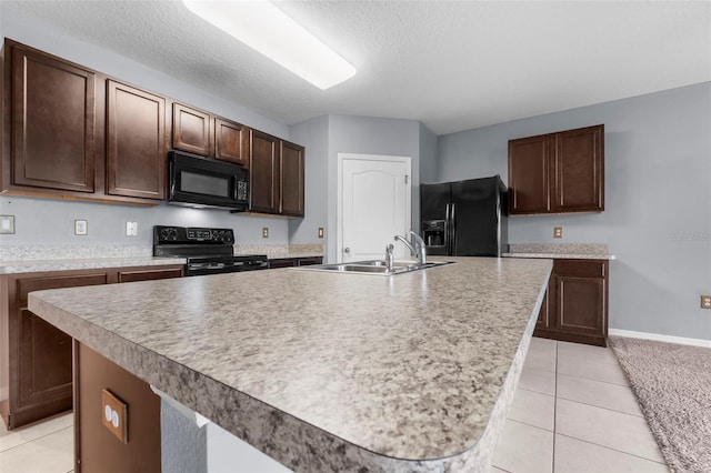 kitchen with a kitchen island with sink, sink, dark brown cabinetry, and black appliances