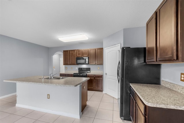 kitchen featuring light tile patterned floors, sink, a center island with sink, and black appliances