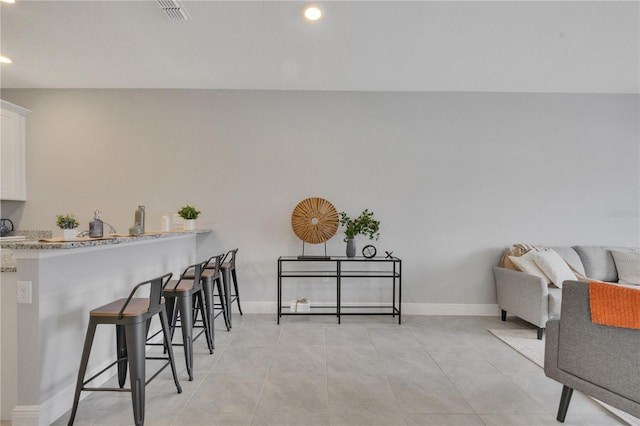 interior space with a breakfast bar, white cabinets, kitchen peninsula, and light tile patterned flooring