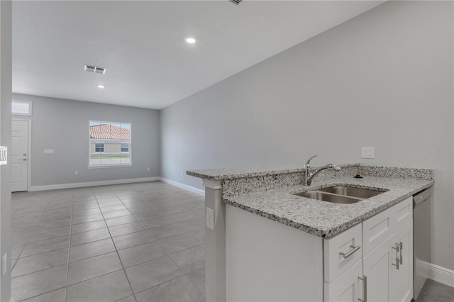 kitchen with sink, white cabinets, light tile patterned floors, light stone countertops, and stainless steel dishwasher