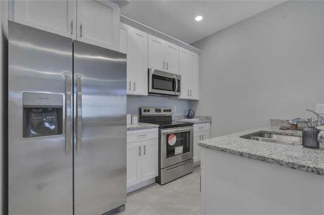 kitchen featuring light stone countertops, sink, stainless steel appliances, and white cabinets