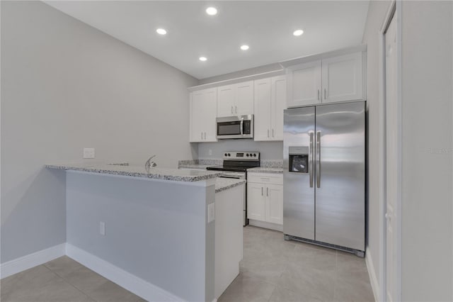 kitchen featuring light stone counters, light tile patterned flooring, kitchen peninsula, white cabinetry, and stainless steel appliances