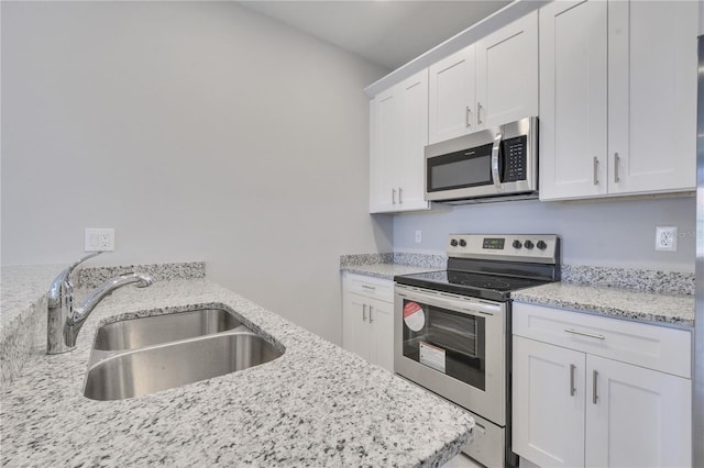 kitchen with appliances with stainless steel finishes, light stone countertops, sink, and white cabinets