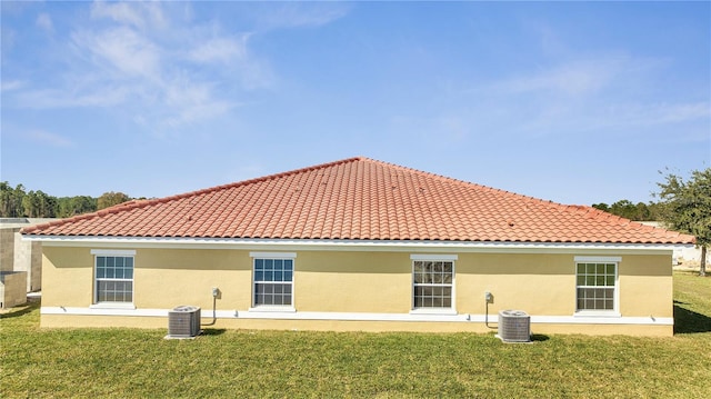 rear view of property with a lawn and central air condition unit