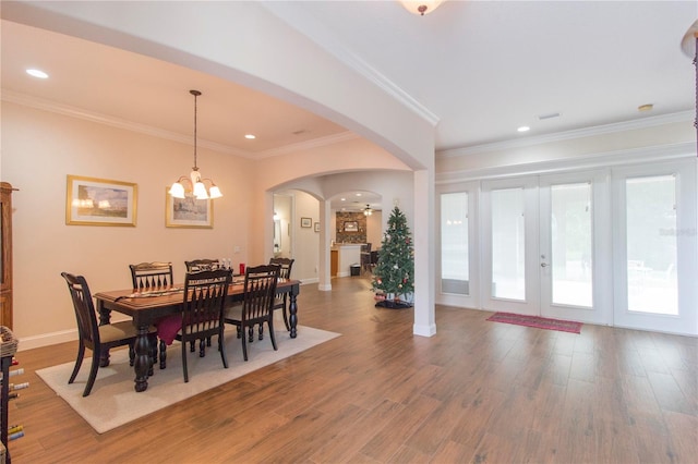 dining room with french doors, crown molding, hardwood / wood-style floors, and ceiling fan with notable chandelier