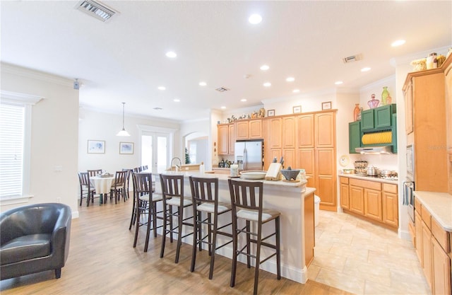 kitchen featuring a center island with sink, hanging light fixtures, crown molding, and appliances with stainless steel finishes