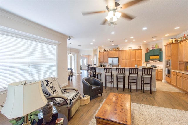 living room featuring crown molding, light hardwood / wood-style flooring, and ceiling fan