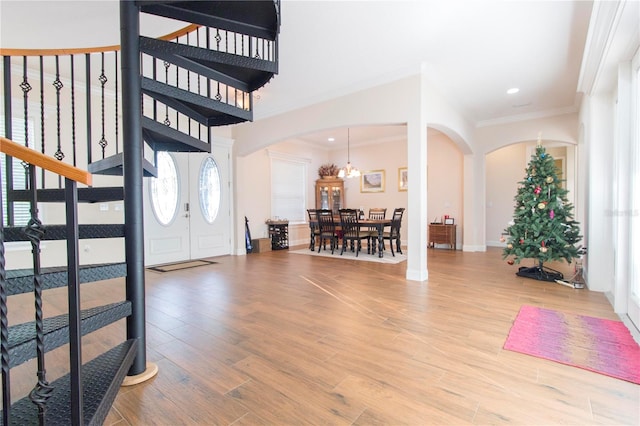 entryway with hardwood / wood-style flooring, crown molding, and an inviting chandelier