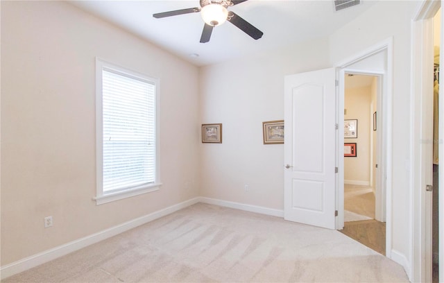 spare room featuring a wealth of natural light, ceiling fan, and light carpet