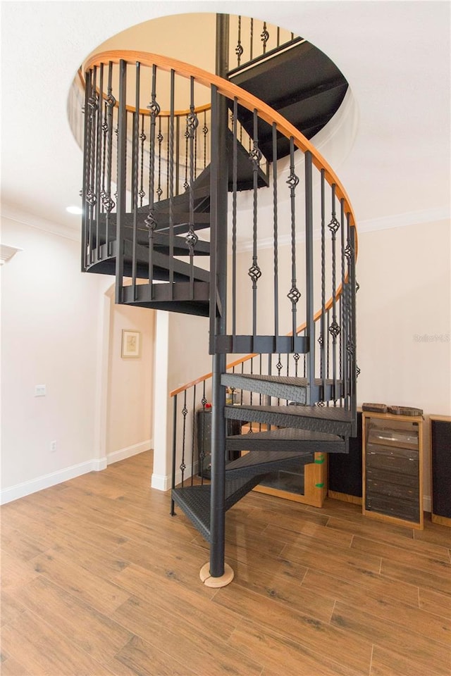 stairway with ornamental molding and hardwood / wood-style flooring