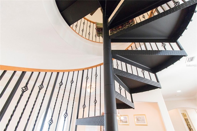 stairs with a towering ceiling and crown molding