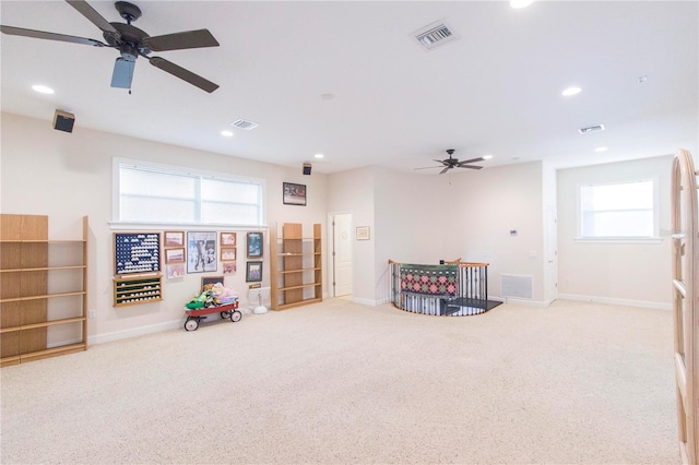 game room with plenty of natural light, ceiling fan, and light carpet