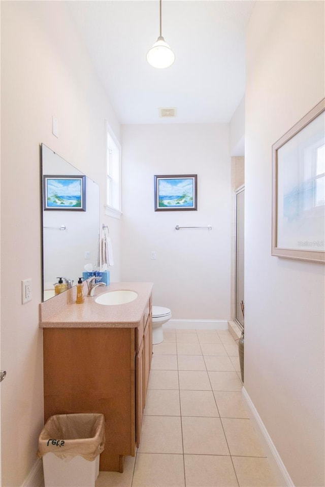 bathroom featuring tile patterned flooring, vanity, toilet, and a shower with shower door