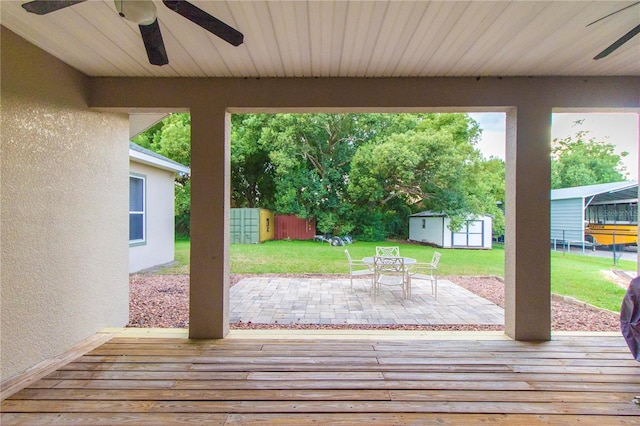 wooden deck with a storage shed, a yard, and a patio