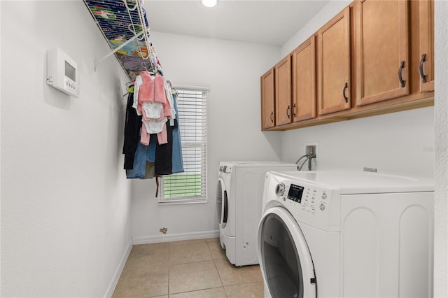 laundry room with washing machine and dryer, light tile patterned flooring, and cabinets