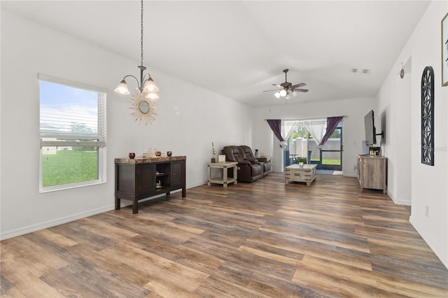 interior space with ceiling fan with notable chandelier, dark wood-type flooring, and a wealth of natural light