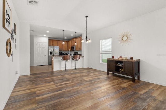 kitchen with appliances with stainless steel finishes, a breakfast bar area, pendant lighting, dark hardwood / wood-style floors, and a chandelier