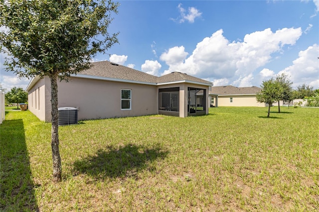 rear view of property featuring a lawn, a sunroom, and central air condition unit