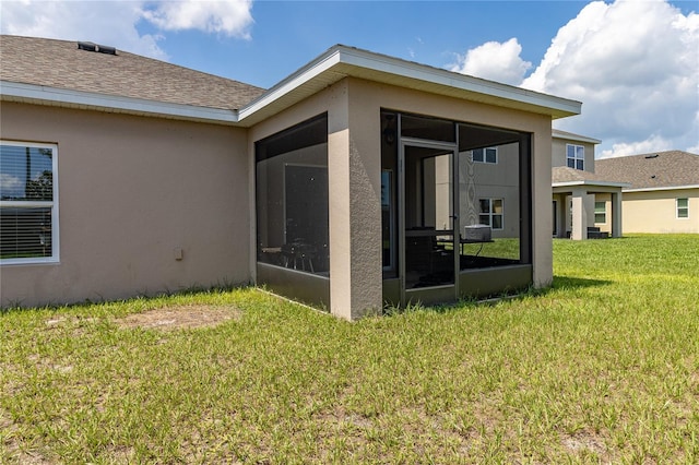 rear view of property featuring a lawn and a sunroom