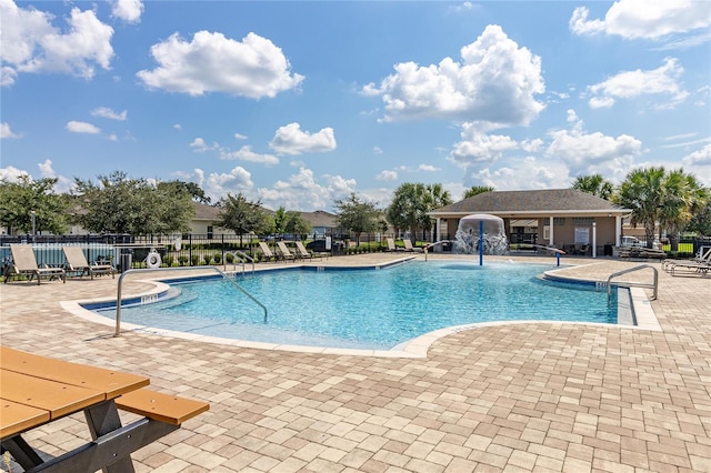 view of swimming pool with pool water feature and a patio area