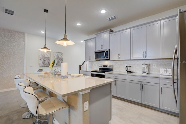 kitchen featuring stainless steel appliances, a kitchen breakfast bar, decorative light fixtures, and decorative backsplash