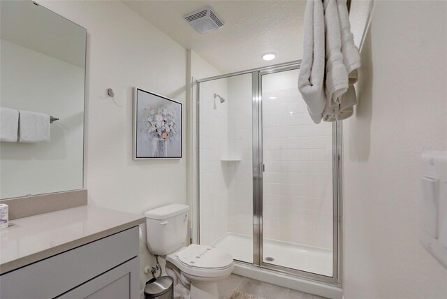 bathroom with toilet, vanity, tile patterned floors, and walk in shower